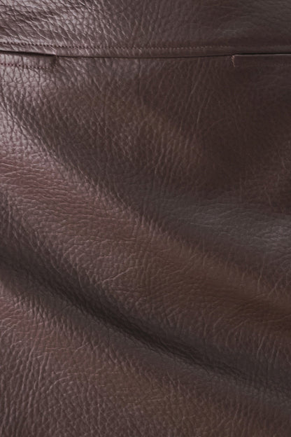 A close-up of dark brown textured leather with visible grain and a horizontal seam.