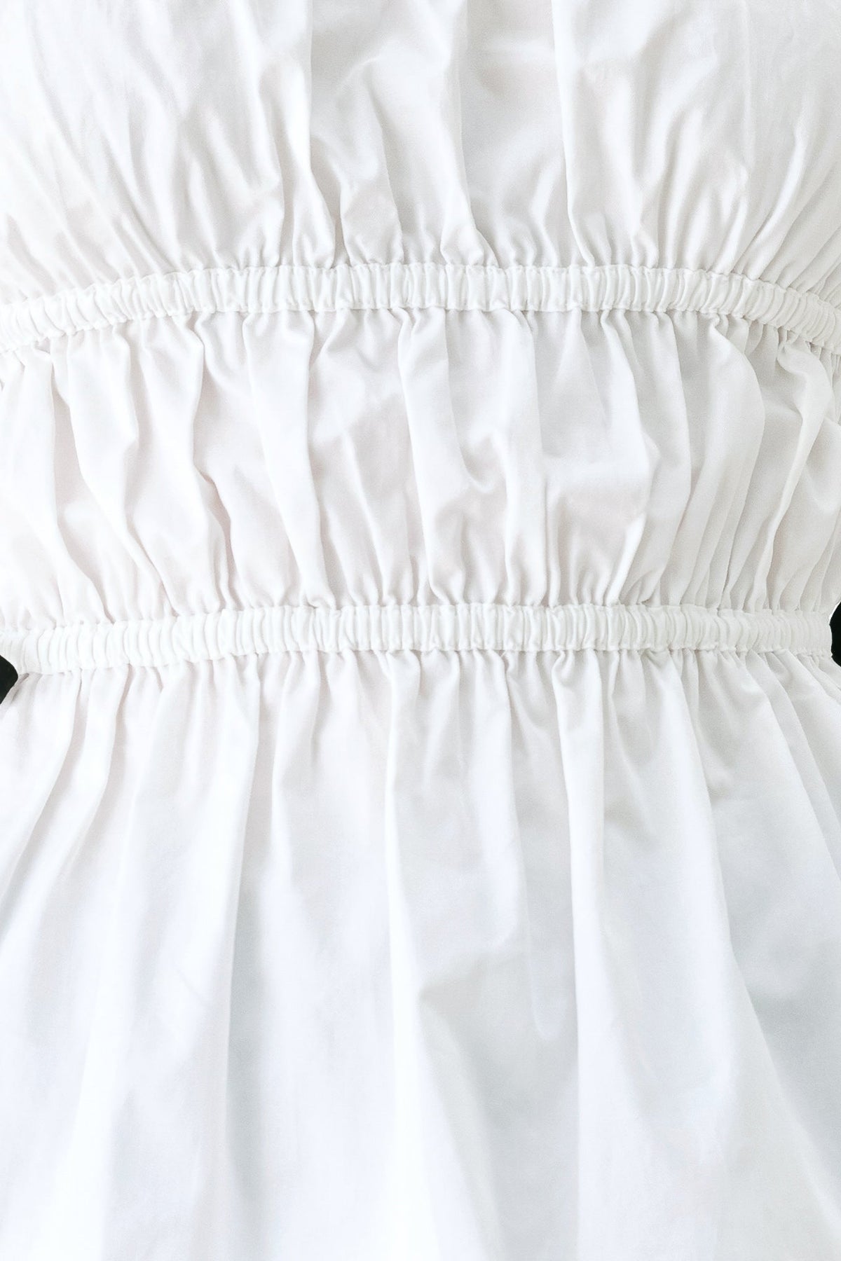 Fabric swatch showing the 100% cotton white woven fabric of the Beach Club strapless top.