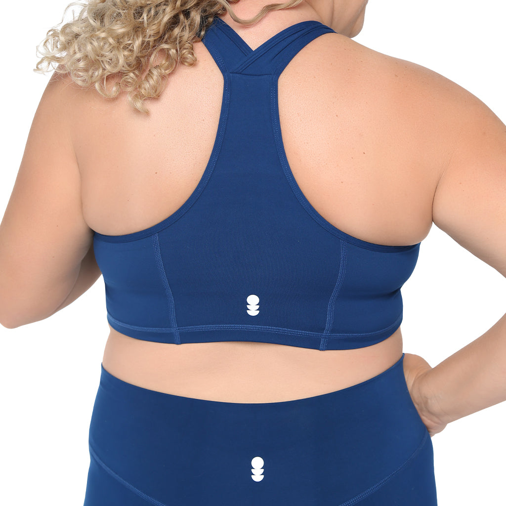 Person wearing a blue sports bra and leggings with a visible brand logo on a white background