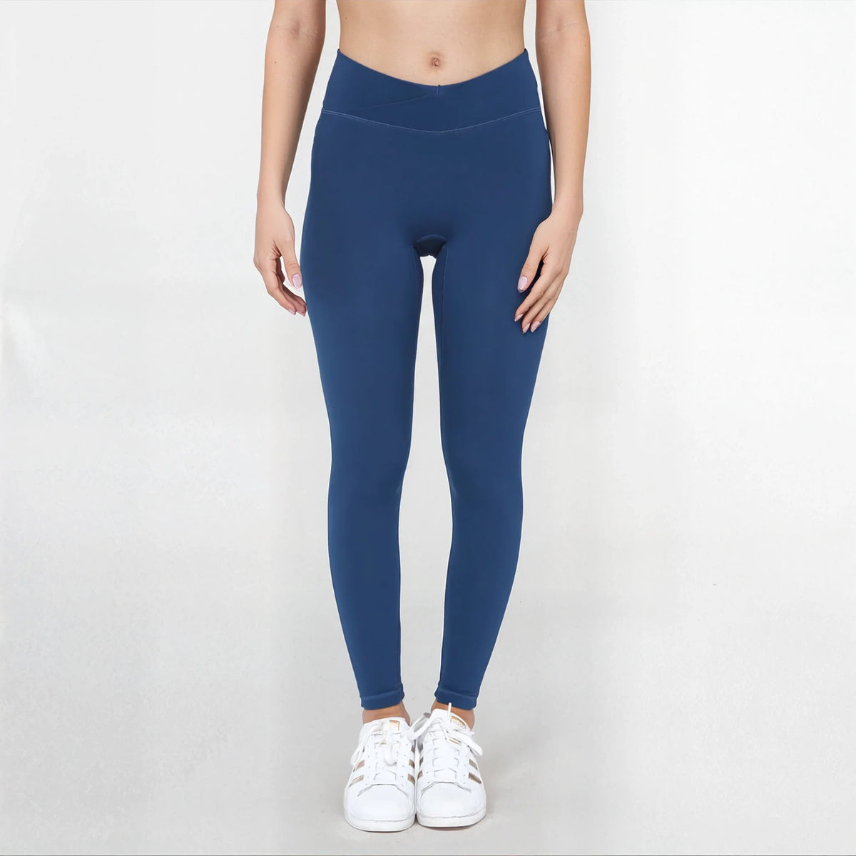 Person wearing blue leggings and white sneakers on a light gray background