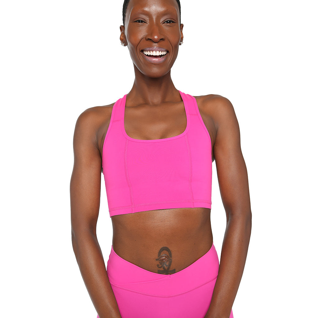 Woman wearing a bright pink sports bra and leggings on a white background