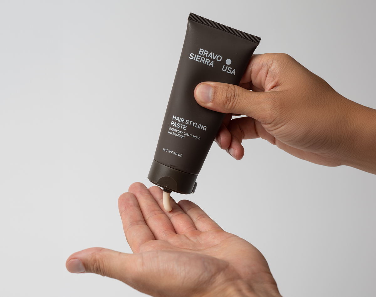 Hand holding a tube of Bravo Sierra USA hair styling paste against a plain background