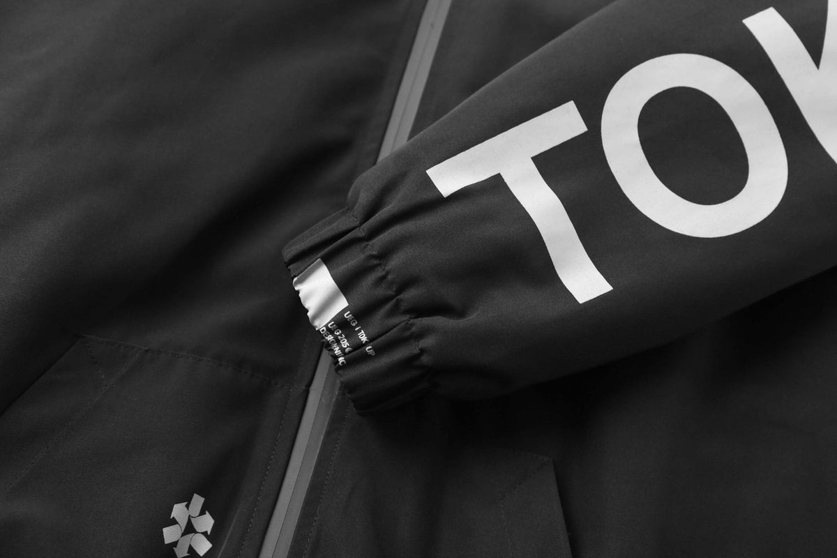 Close-up of a black jacket with 'TOKYO' branding on a dark background