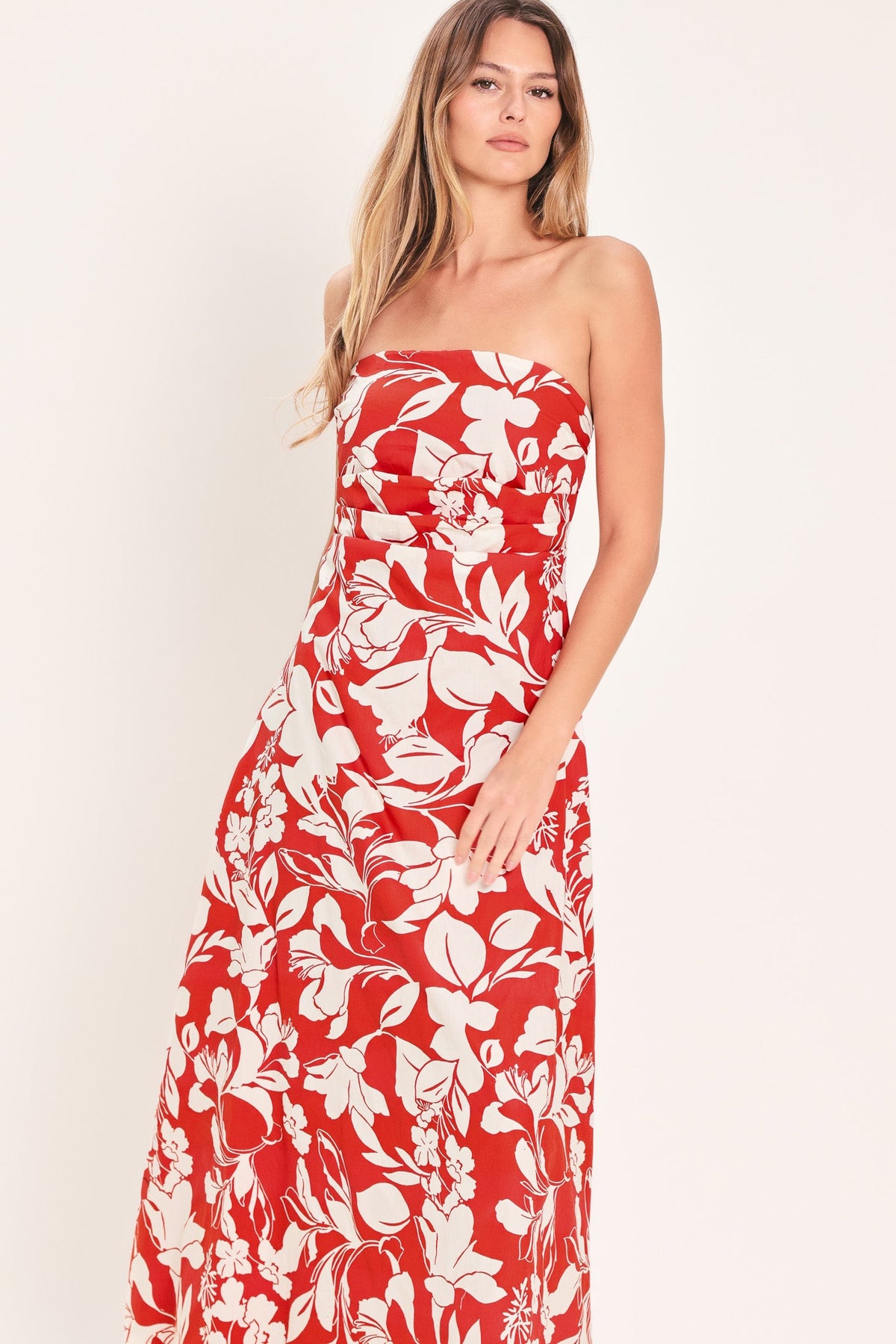 Woman wearing a strapless red floral dress against a white background