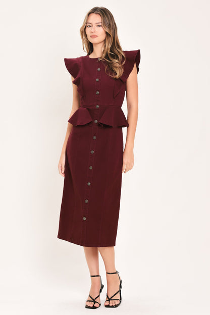 A woman modeling a sleeveless burgundy midi dress with ruffled cap sleeves, a peplum waist, and a front button placket, paired with black strappy heels against a plain off-white studio background.