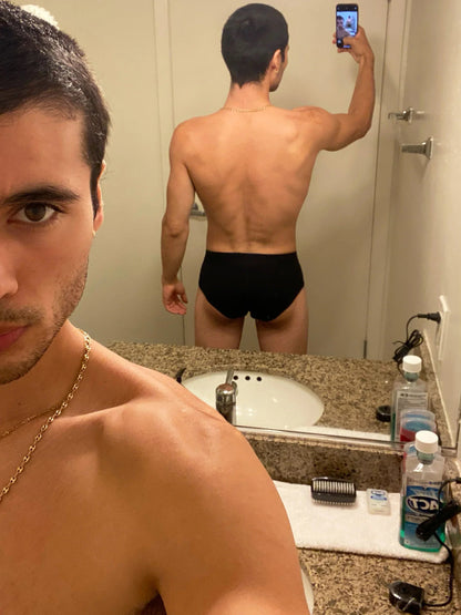 Man taking a mirror selfie in a bathroom wearing black underwear.
