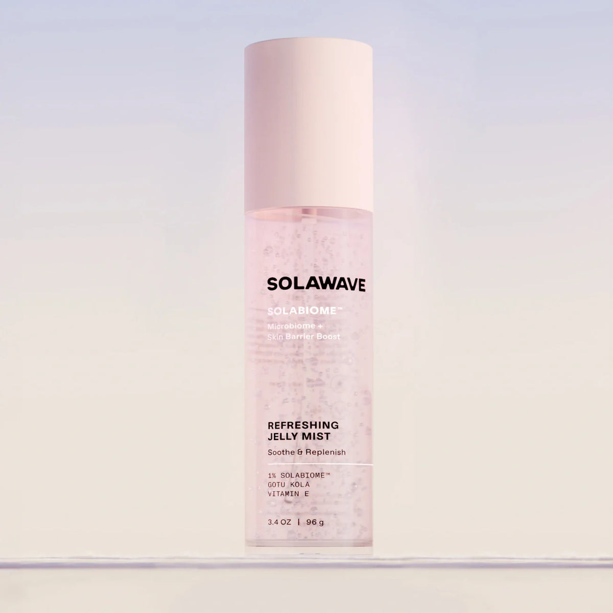 Solawave Solabiome Refreshing Jelly Mist bottle with a pale pink cap, centered against a soft light blue and white gradient background