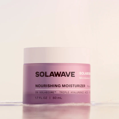 A jar of Solawave Nourishing Moisturizer with a light pink body and a white lid, set against a clean, off-white background.