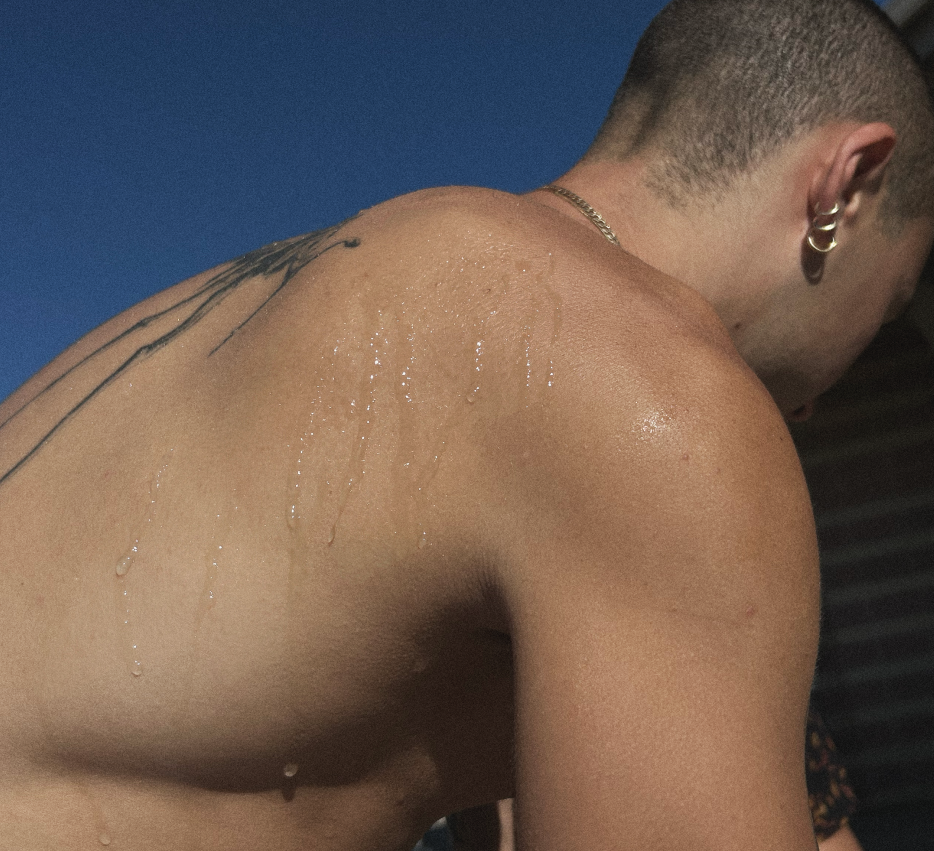 Man with a tattoo on his shoulder against a blue sky