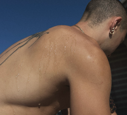 Man with a tattoo on his shoulder against a blue sky