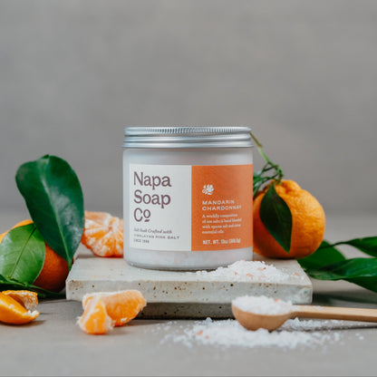 Mandarin Chardonnay bath salt soak with mandarin oranges and loose salt on a gray background