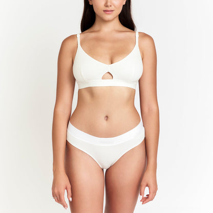 Woman wearing a white bikini set on a plain background