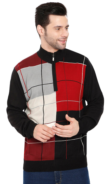 A man wearing a quarter-zip knit sweater with a geometric color-block pattern in black, red, gray, and off-white, paired with blue jeans against a plain white background.