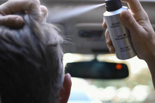Person using a bottle of dry shampoo inside a car.