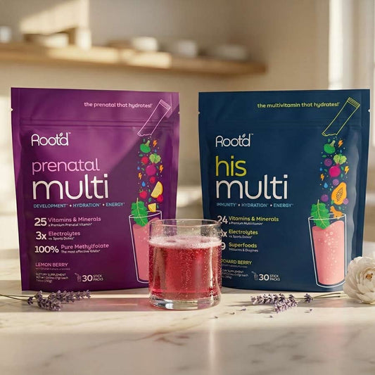 Two stand-up pouches of Aooda prenatal multi and his multi multivitamin drinks displayed on a marble surface with a glass of pink beverage in front, set against a softly blurred kitchen background.