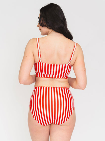Woman wearing a red and white striped bikini set on a plain background