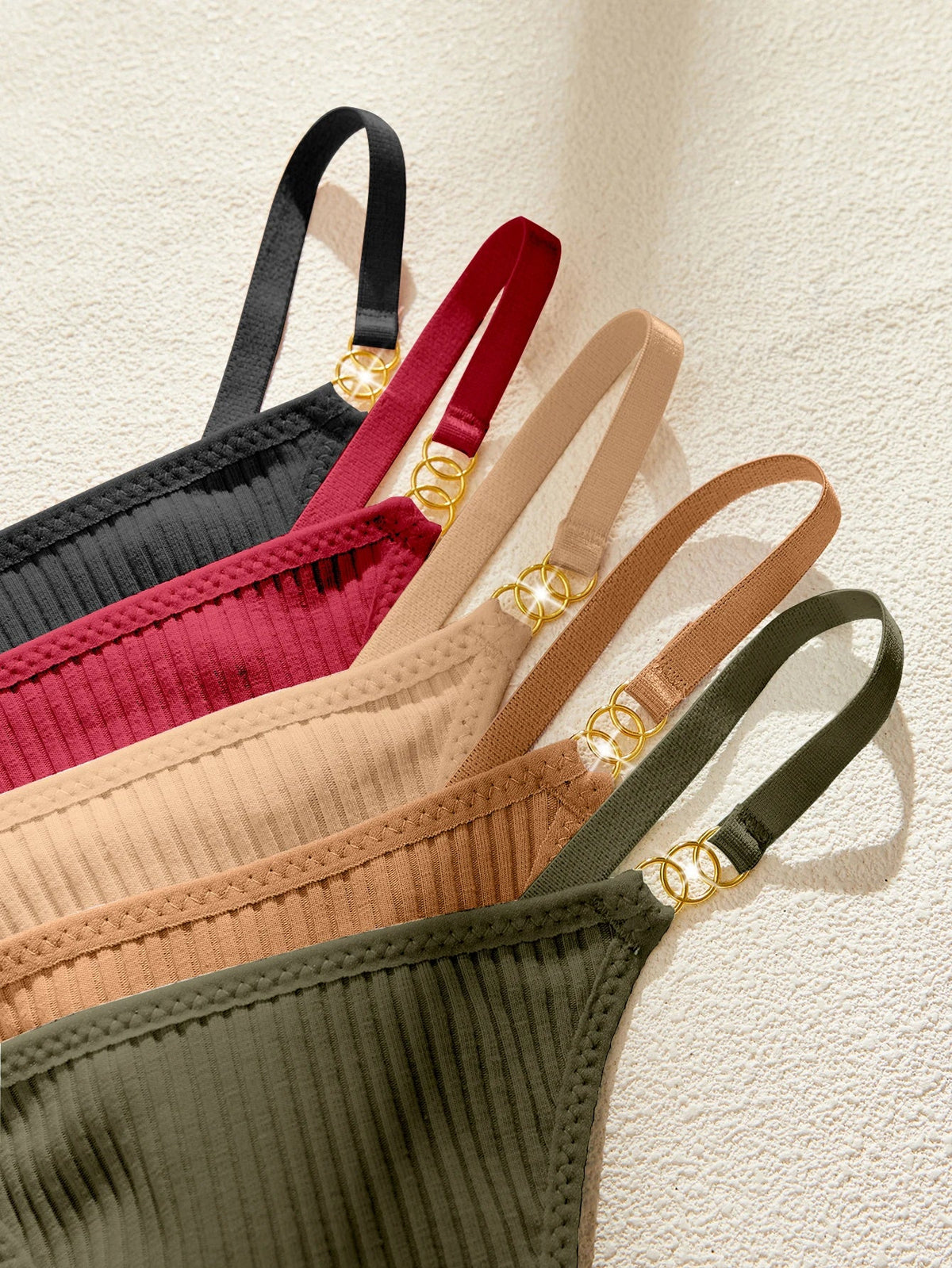 Set of four bras in black, red, beige, and green on a light background
