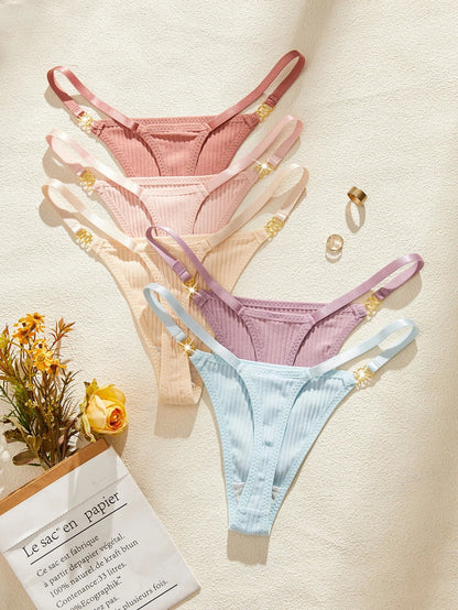 Set of pastel-colored women's underwear on a light background with flowers and a book.