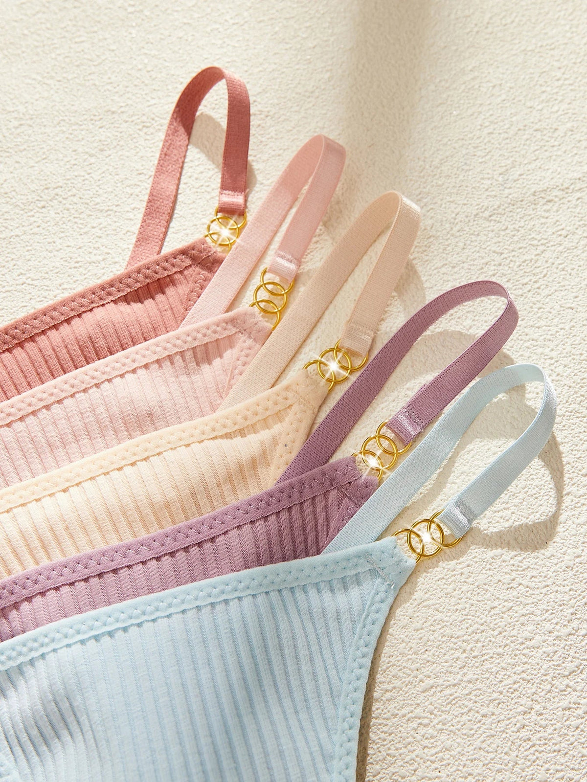 Set of pastel-colored bras with thin straps on a light background