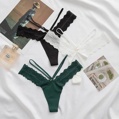 Green and black lace lingerie set on a white fabric background with a magazine and perfume bottle.