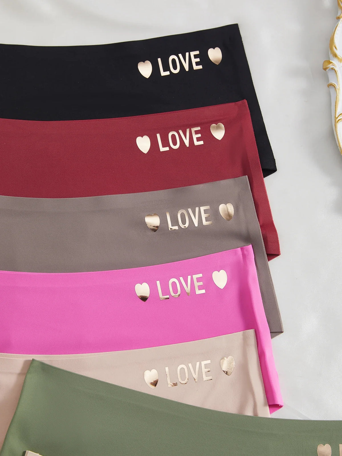 Four pairs of underwear with 'LOVE' and heart designs on a light gray background