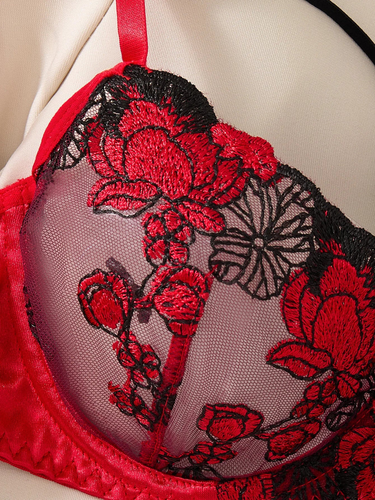 Red and black floral embroidered bralette on a neutral background
