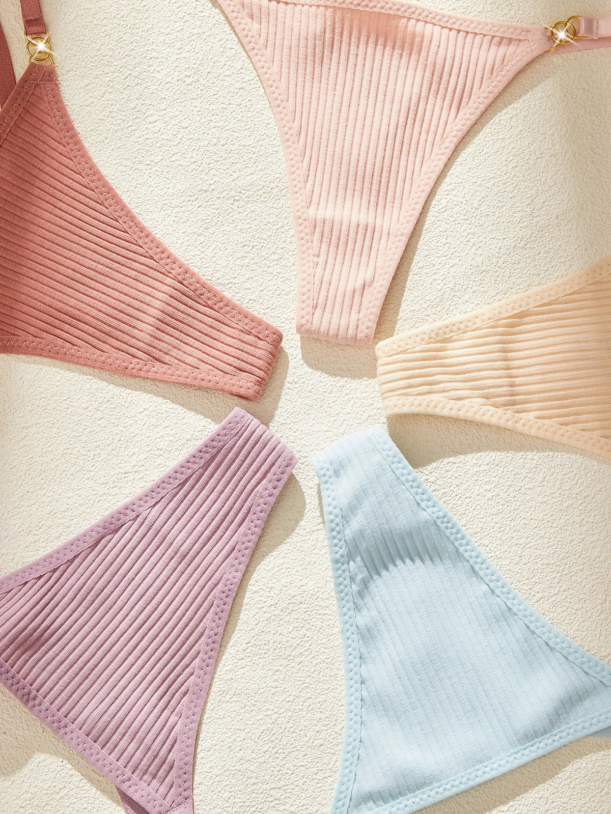 Set of ribbed underwear in various colors on a textured beige background