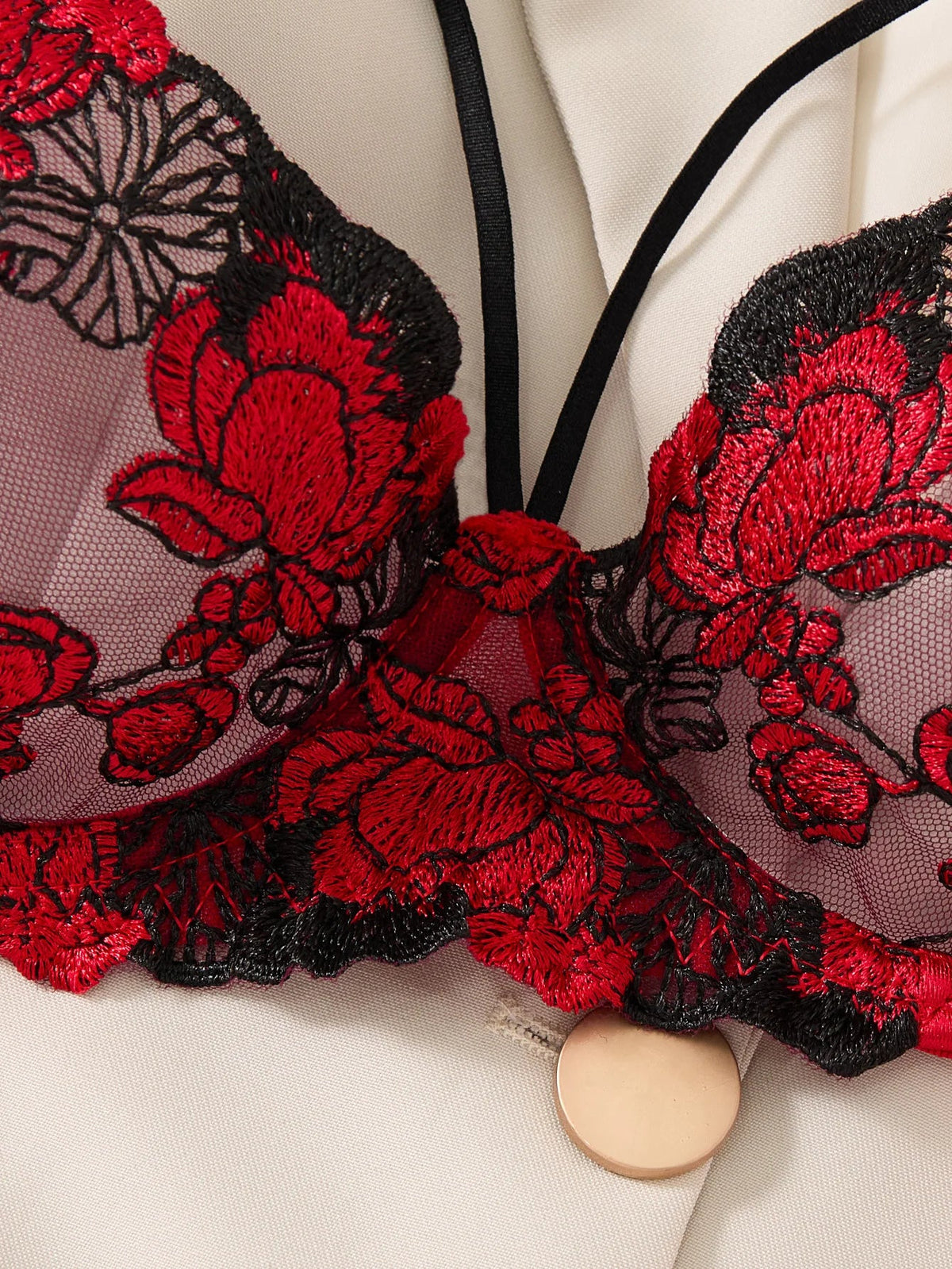 Close-up of a red and black floral embroidered garment on a white background
