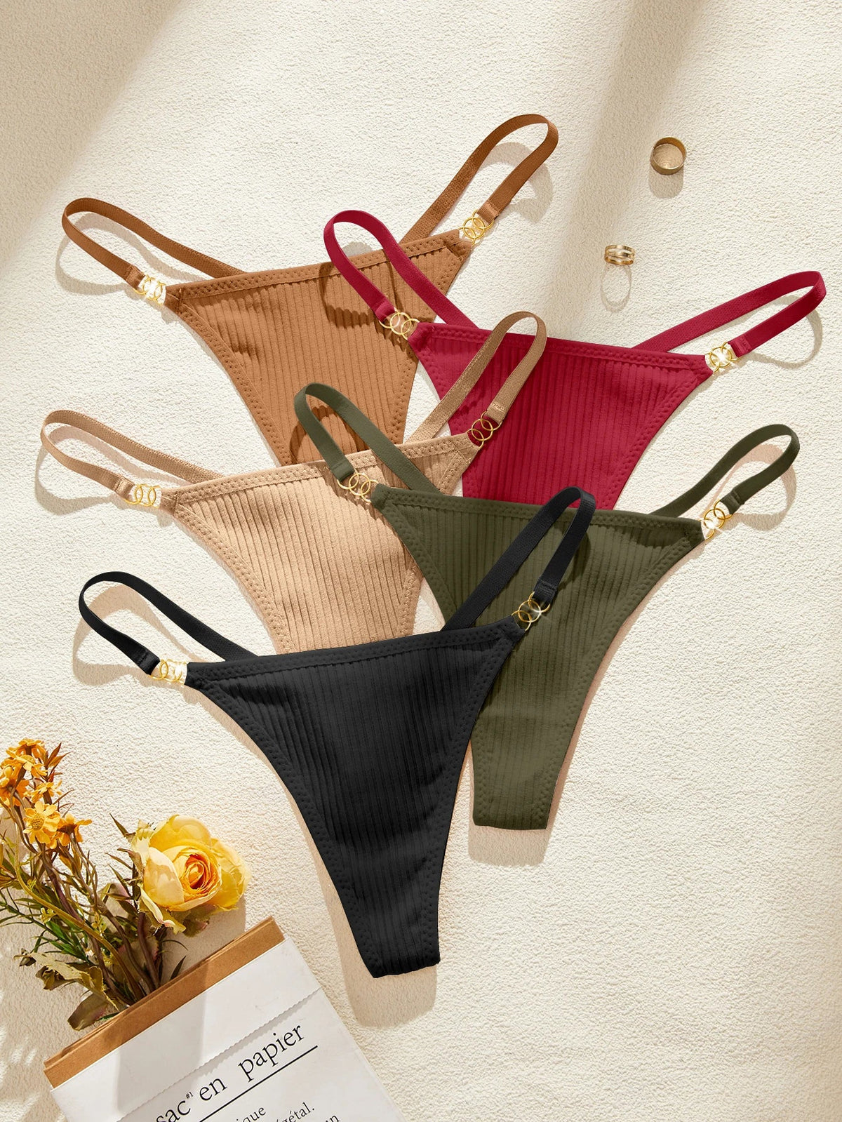 Four ribbed bikini bottoms in black, green, beige, and red on a light background.