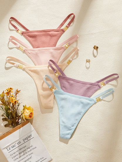 Four pairs of colorful ribbed thongs on a textured surface with flowers and a card.