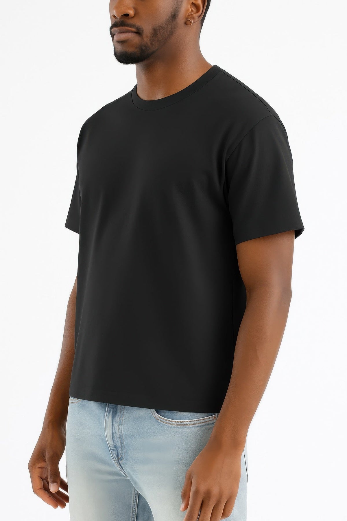 Man wearing a black t-shirt and light blue jeans on a white background