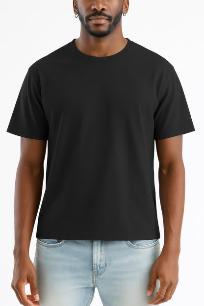 Man wearing a black t-shirt and light blue jeans on a white background