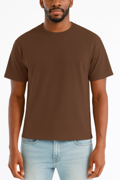 Man wearing a brown t-shirt and light blue jeans on a white background