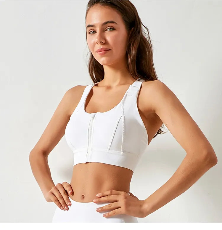 Woman wearing a white sports bra and leggings on a plain background