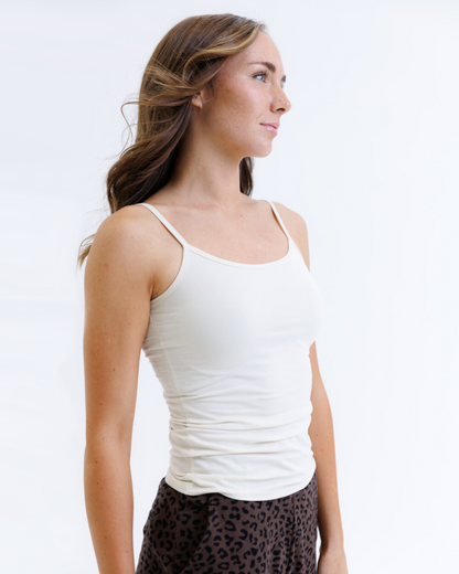 Woman wearing a white tank top against a plain background