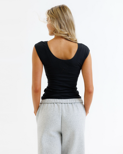 Woman wearing a black tank top and gray sweatpants on a white background