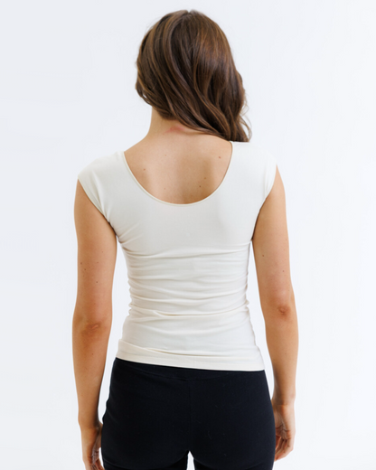 Person wearing a white top and black pants on a plain background