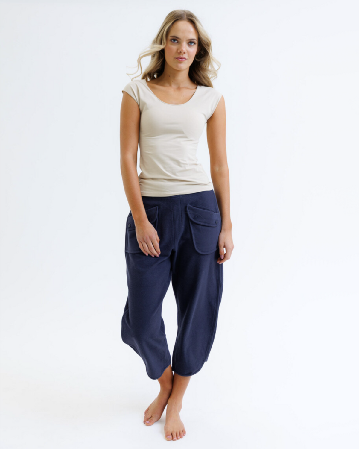 Woman wearing a white top and navy blue pants on a white background