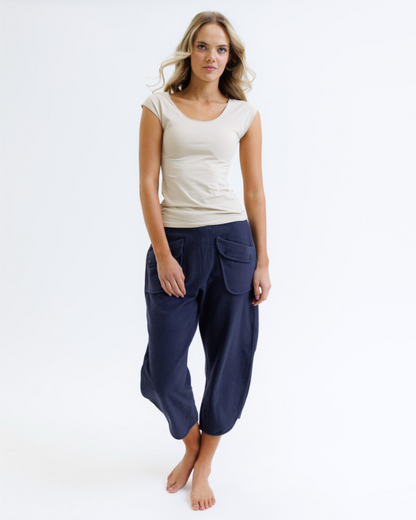 Woman wearing a white top and navy blue pants on a white background