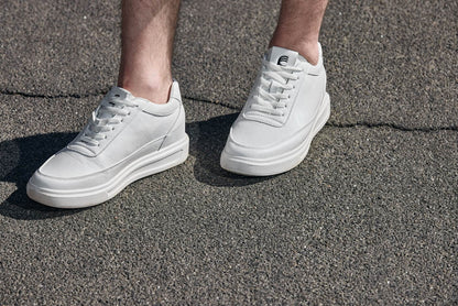 White sneakers on a person's feet standing on a concrete surface