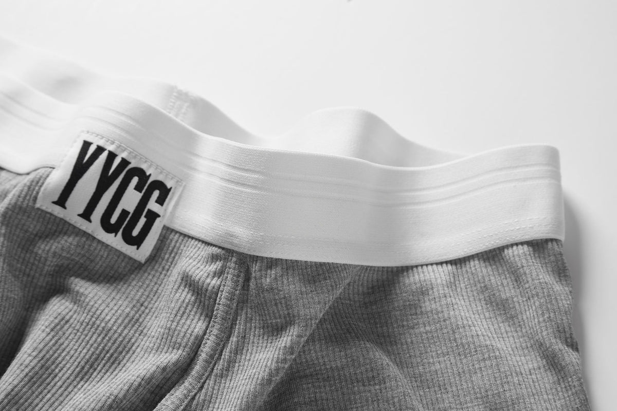 Gray boxer briefs with a white waistband featuring 'YYCG' branding on a light gray background.