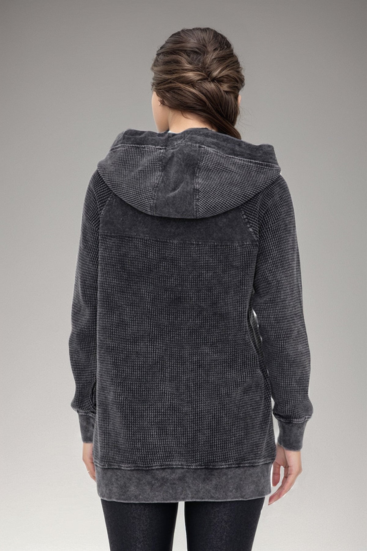 Person wearing a gray textured hoodie against a neutral background