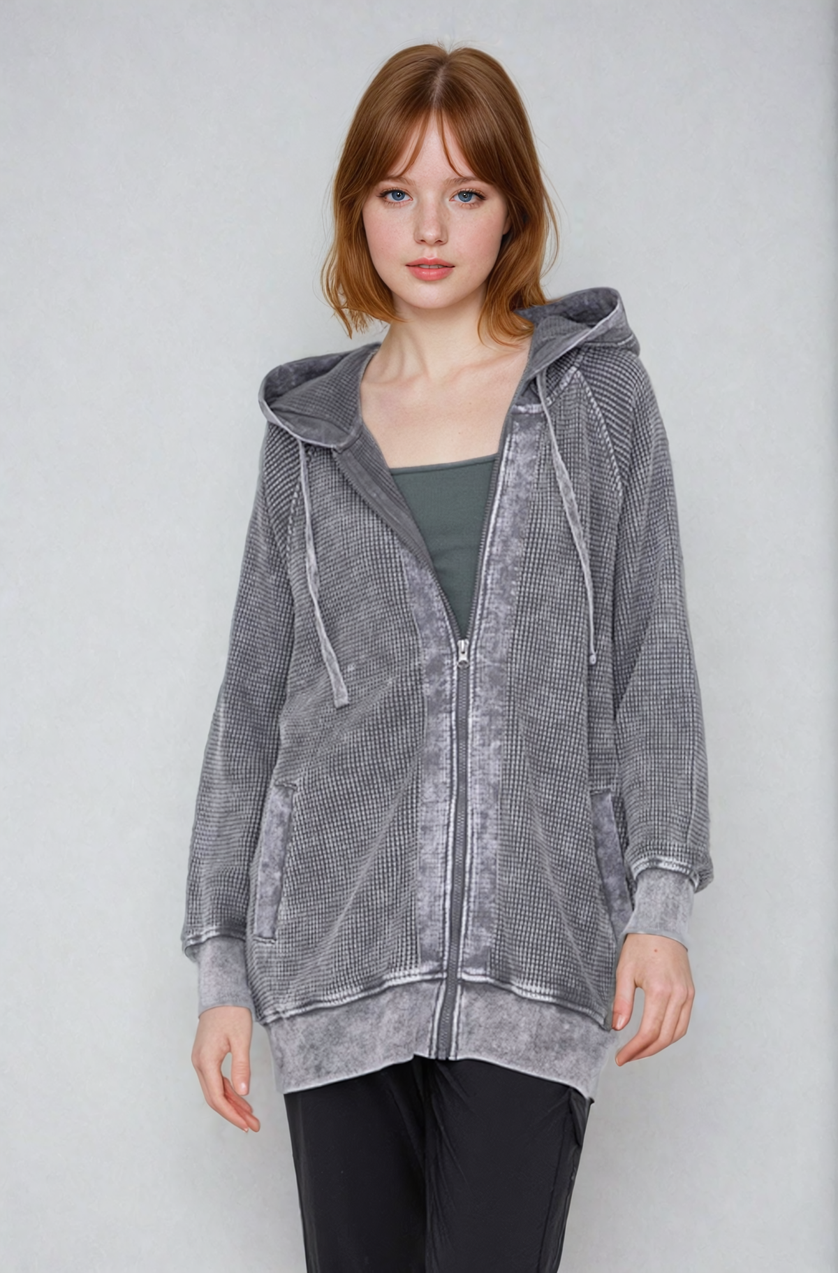 Woman wearing a gray hooded jacket against a plain background