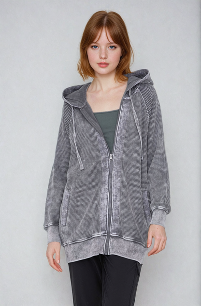 Woman wearing a gray hooded jacket against a plain background