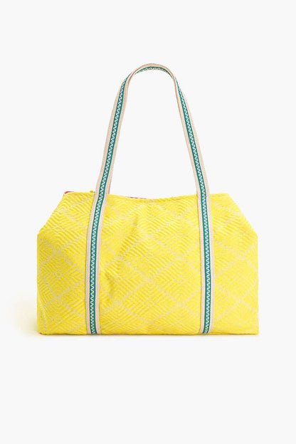 Yellow quilted handbag with green accents on a white background