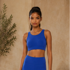 Woman wearing a blue athletic outfit standing against a beige wall.