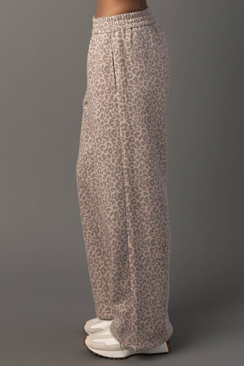 Leopard print pants worn by a person on a gray background
