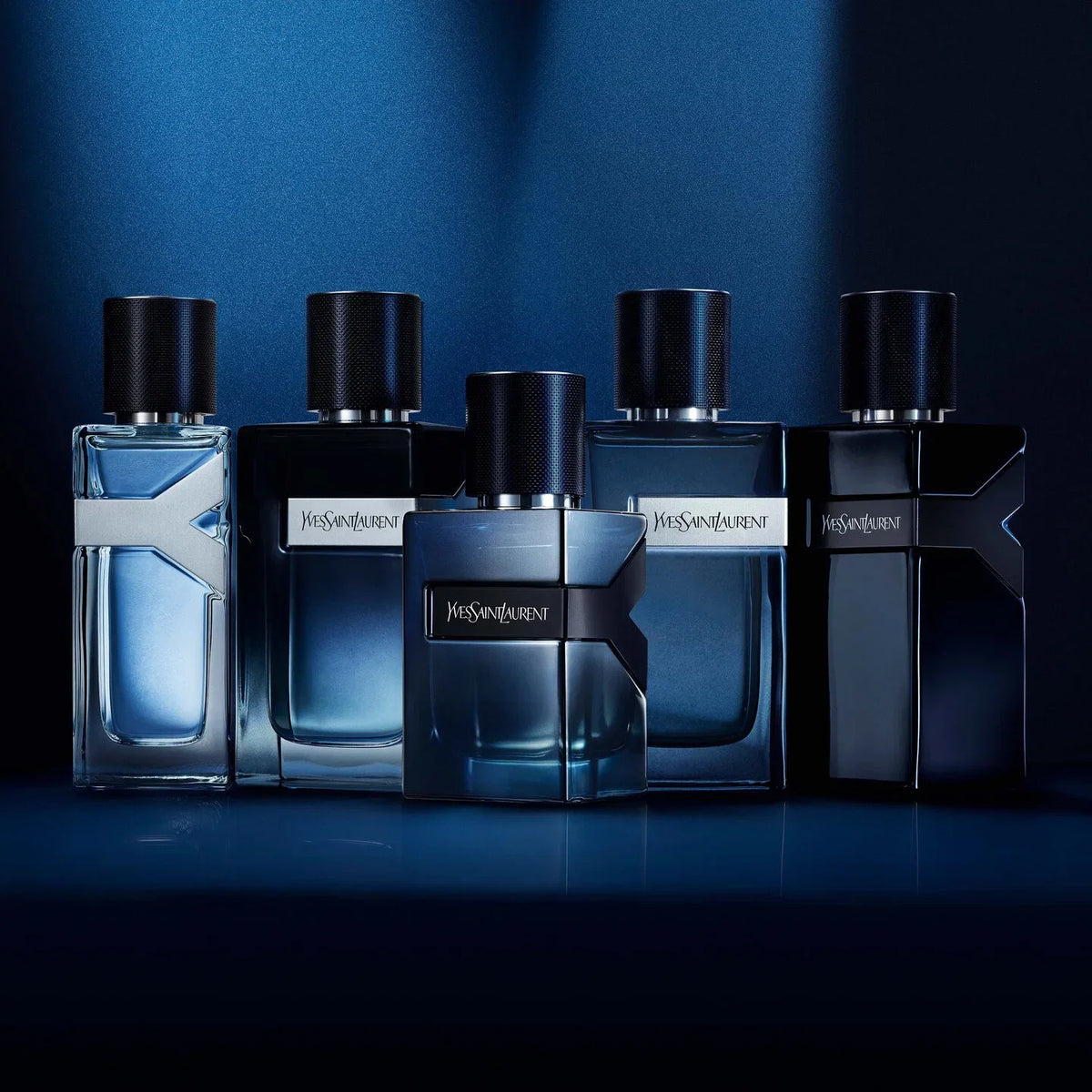 Five Yves Saint Laurent perfume bottles on a dark blue background
