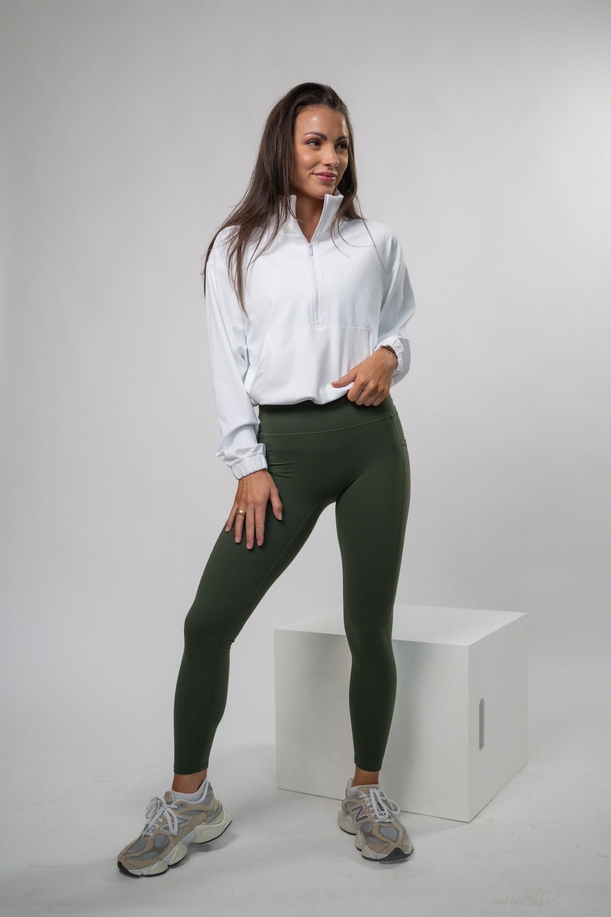 Woman wearing a white shirt and green leggings standing on a white background