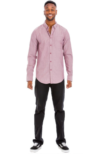 Man wearing a pink button-up shirt and black pants on a white background